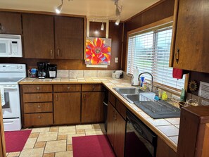 A kitchen with wooden cabinets, a microwave, a coffee maker, and a dishwasher. -  Beach cabin in Yachats perfect for relaxing getaways (Yachats)