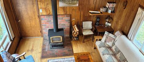 A cozy cabin interior with a fireplace, wooden walls, a sofa, and a television.