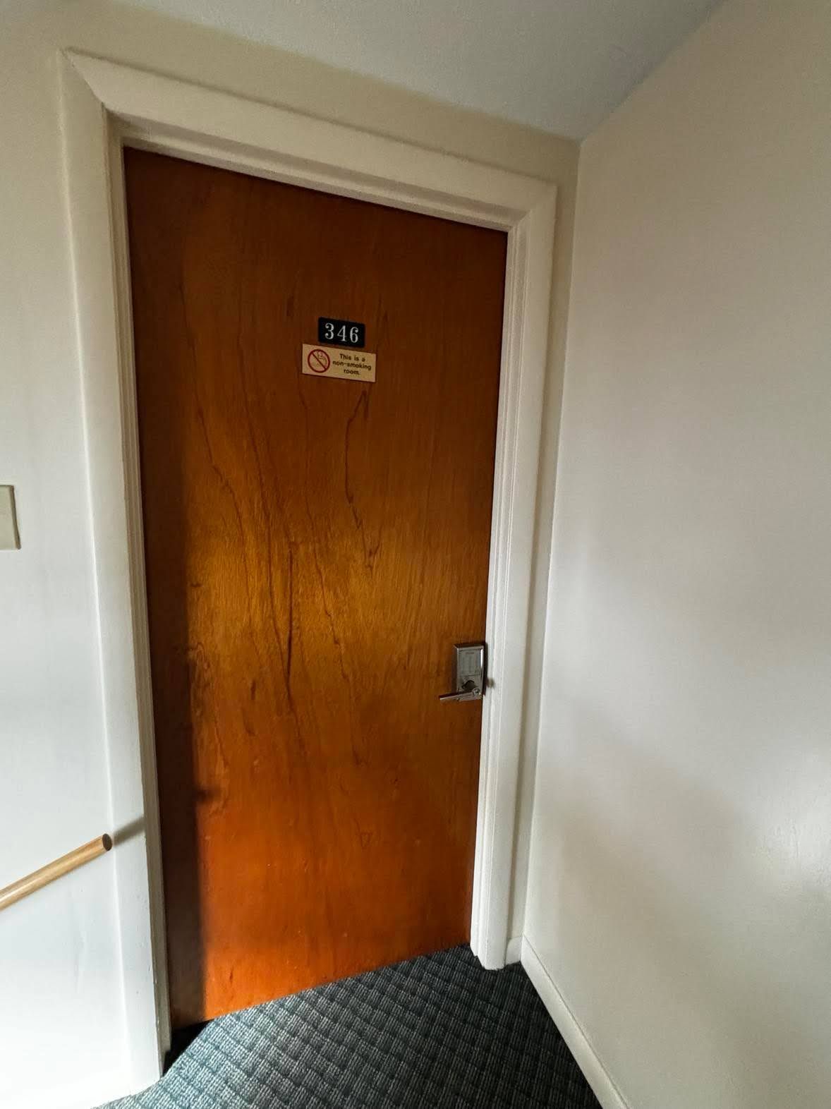 Une porte en bois avec un panneau indiquant qu’il est interdit de fumer et le numéro de chambre : 346.