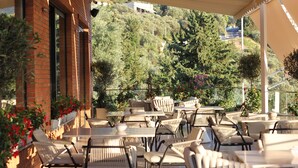 An outdoor cafe with wicker furniture and a view of a hillside.