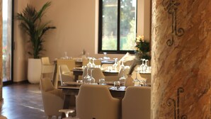 A dining area with tables set for a meal, chairs, and a large window with a view.