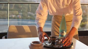 A person setting a table with a bottle, glasses, and a bowl.