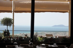Comedor con una mesa dispuesta para dos personas, con vistas a la ciudad y al mar.