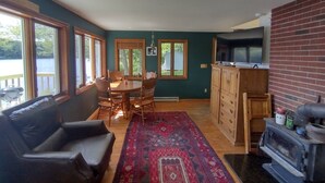 Ein Wohnzimmer mit Kamin, ein Essbereich mit Tisch und Stühlen sowie eine Küchenzeile mit Schränken und Herd.