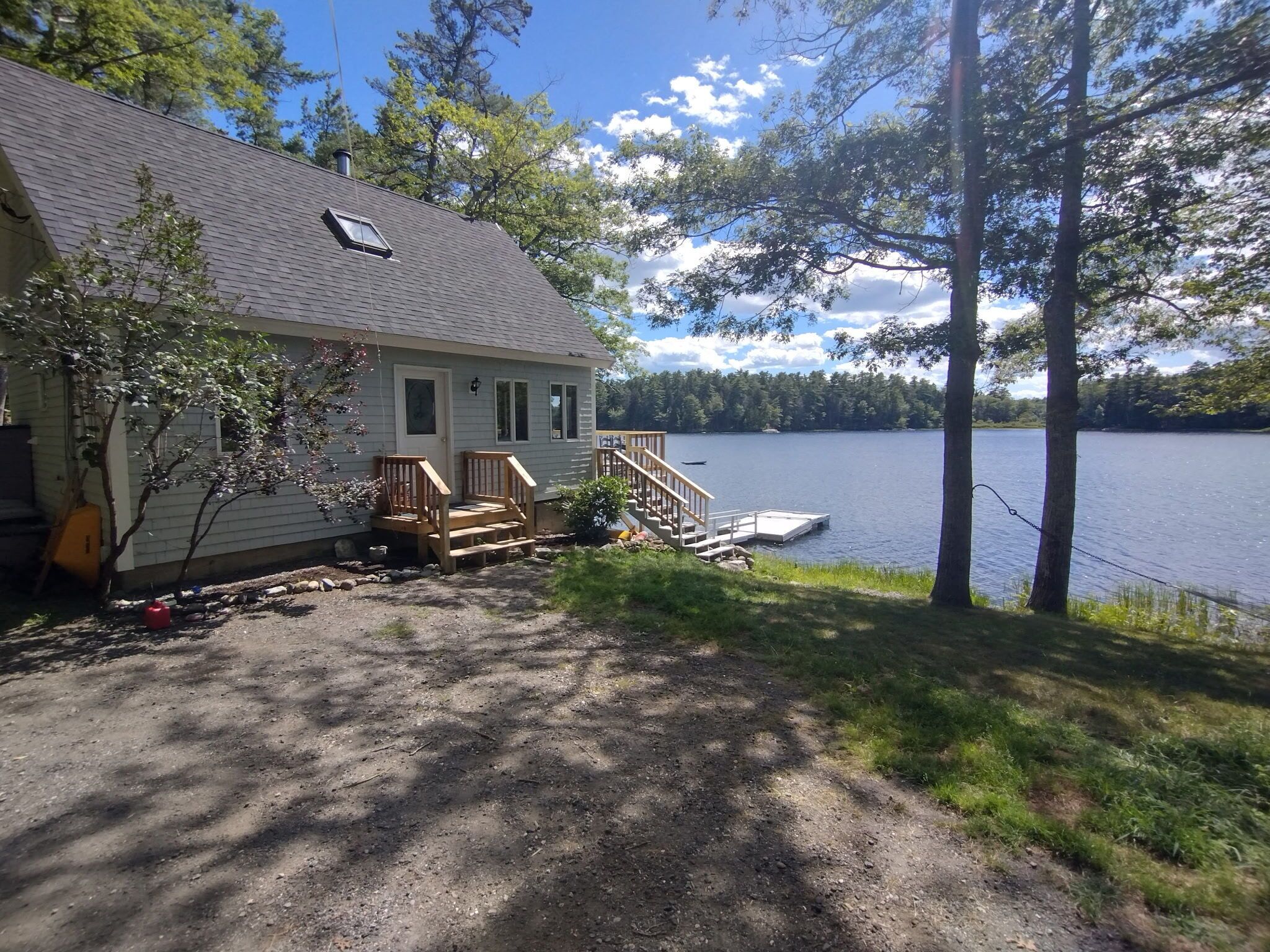 Ett hus med en brygga som sträcker sig ut i en sjö, omgivet av träd.