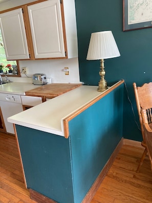Una cocina con encimera de madera, un armario blanco, una lámpara de latón y una pared azul.