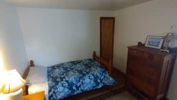 A small bedroom with a bed, a dresser, a nightstand, and a lamp.