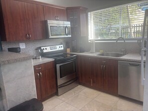 A kitchen with wooden cabinets, a stainless steel microwave, a stove, and a dishwasher. - Heart of Wynwood Spacious 2bedroom #3 (Miami)