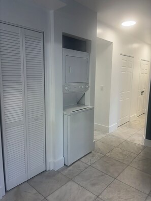 A laundry room with a built-in washer and dryer, a white door, and a tiled floor. - Heart of Wynwood Spacious 2bedroom #3 (Miami)