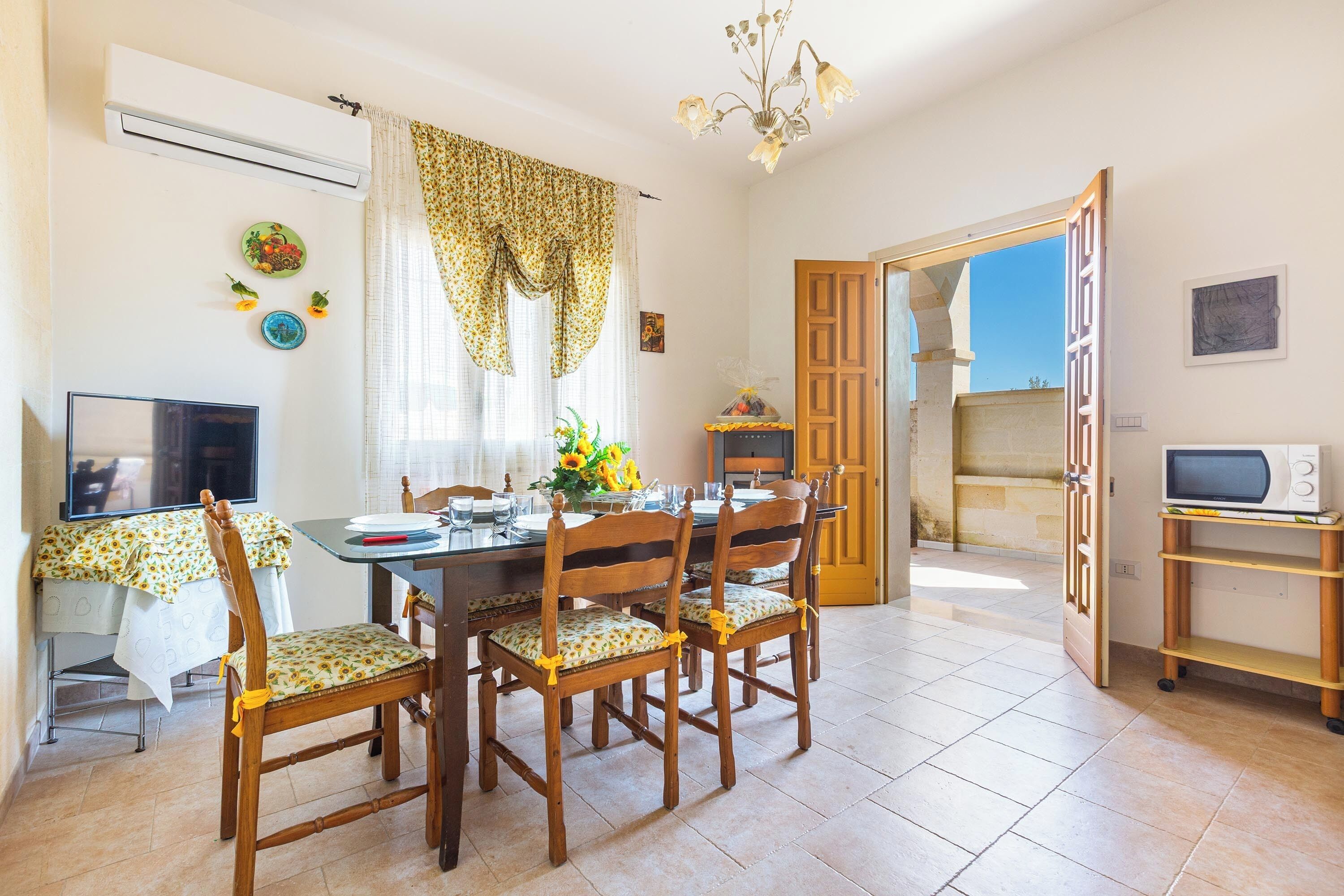 A dining area with a table set for four, surrounded by wooden chairs with floral cushions.