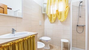 A bathroom with a sink, toilet, shower, and a yellow curtain. - Villetta Lea by BarbarHouse (San Pietro in Bevagna)