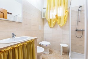 A bathroom with a sink, toilet, shower, and a yellow curtain. - Villetta Lea by BarbarHouse (San Pietro in Bevagna)