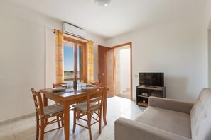 A living room with a sofa, a TV, and a dining area with a table and chairs. - Villino dei Saraceni by BarbarHouse (Torre dell'Orso)