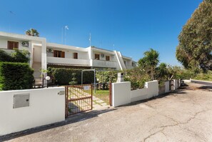 A two-story residential building with a gated entrance, a small patio area, and a clear sky. - Villino dei Saraceni by BarbarHouse (Torre dell'Orso)