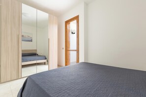 A bedroom with a bed, a wardrobe, and a door leading to another room. - Villino dei Saraceni by BarbarHouse (Torre dell'Orso)