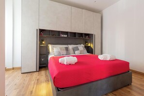 A modern bedroom with a large bed, grey headboard, and built-in shelving. - Due Passi dal Vaticano by BarbarHouse (Roma)