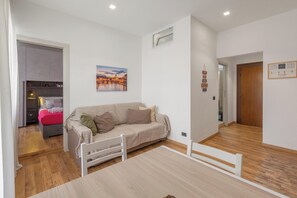 A modern living room with a sofa, a dining table, and a kitchen in the background. - Due Passi dal Vaticano by BarbarHouse (Roma)