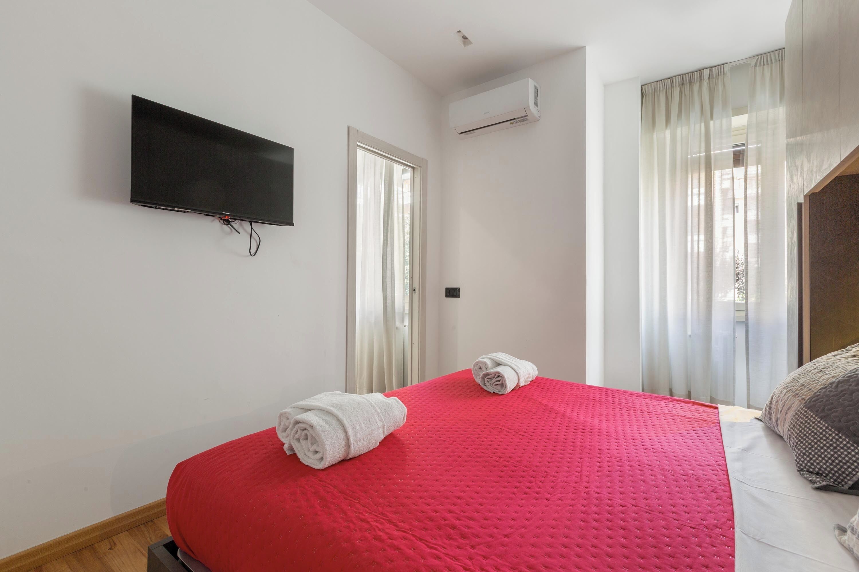 Een hotelkamer met een bed, een wandtelevisie en een airconditioner.