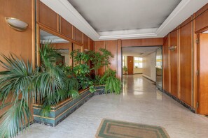 Un pasillo con paneles de madera, plantas en macetas y suelo de mármol.