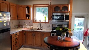 A kitchen with wooden cabinets, a stainless steel refrigerator, a microwave, an oven, and a dining table with chairs. - Otto Street, Osgoode. (osgoode)