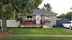 Ein eingeschossiges Haus mit Veranda, Garage und einem Zelt auf der Einfahrt.