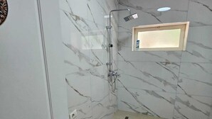 Une salle de bain avec douche, toilettes et murs en marbre.