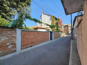 A narrow street with brick walls and a building with a white facade and red-tiled roof.