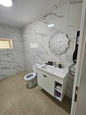 Une salle de bain avec des toilettes, un lavabo et un miroir.