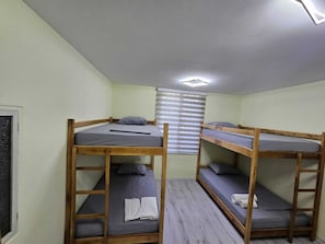 Un dormitorio con literas, una ventana con persianas y una lámpara en el techo.