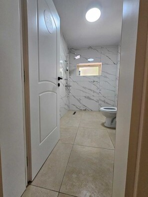 Baño con inodoro, ducha y una ventana pequeña.