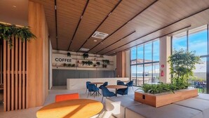 A modern coffee shop with a wooden ceiling, a coffee bar, and seating areas with blue chairs and a wooden table. - Studio in Condo. w/ Pool Near the Beach Bea0207 (Salvador)