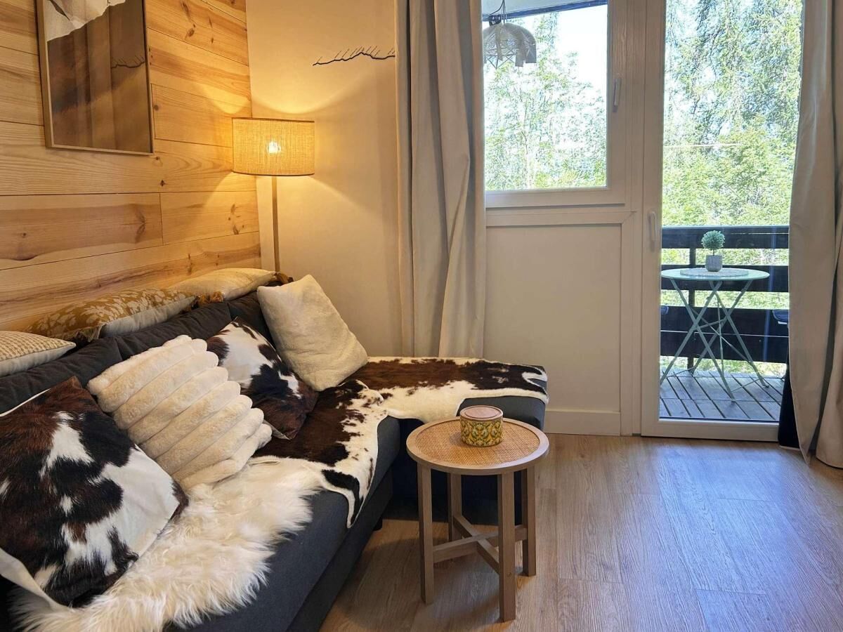 Ein gemütliches Zimmer mit einer Couch, einem kleinen runden Tisch und Blick auf eine Terrasse.