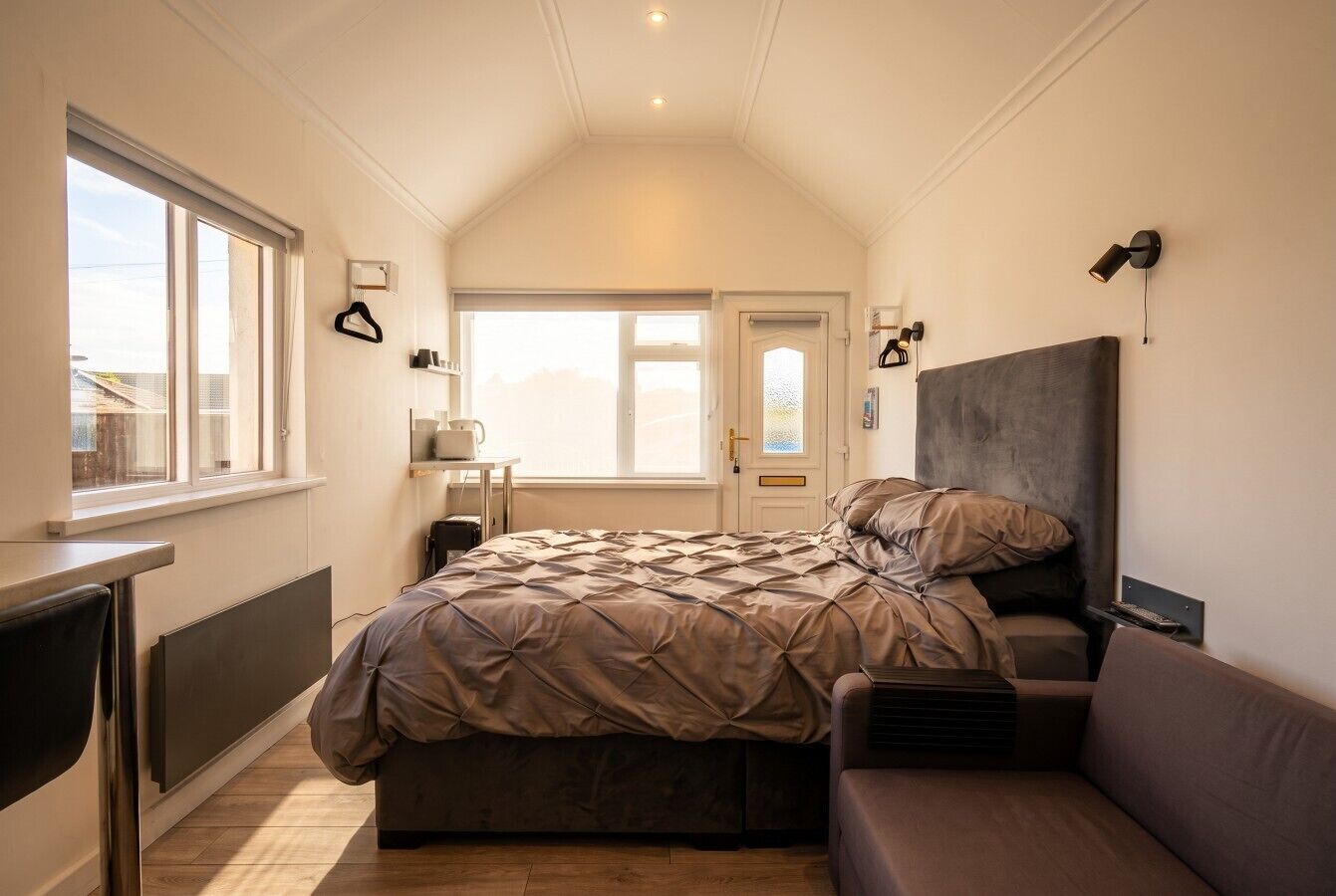Ein Schlafzimmer mit Bett, Sofa, Schreibtisch und Fenster.