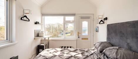 Une chambre à coucher avec un lit, un bureau, une chaise et une fenêtre.