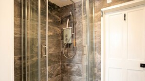 Eine Dusche mit Glastüren, eine weiße Tür und eine Marmorwand.
