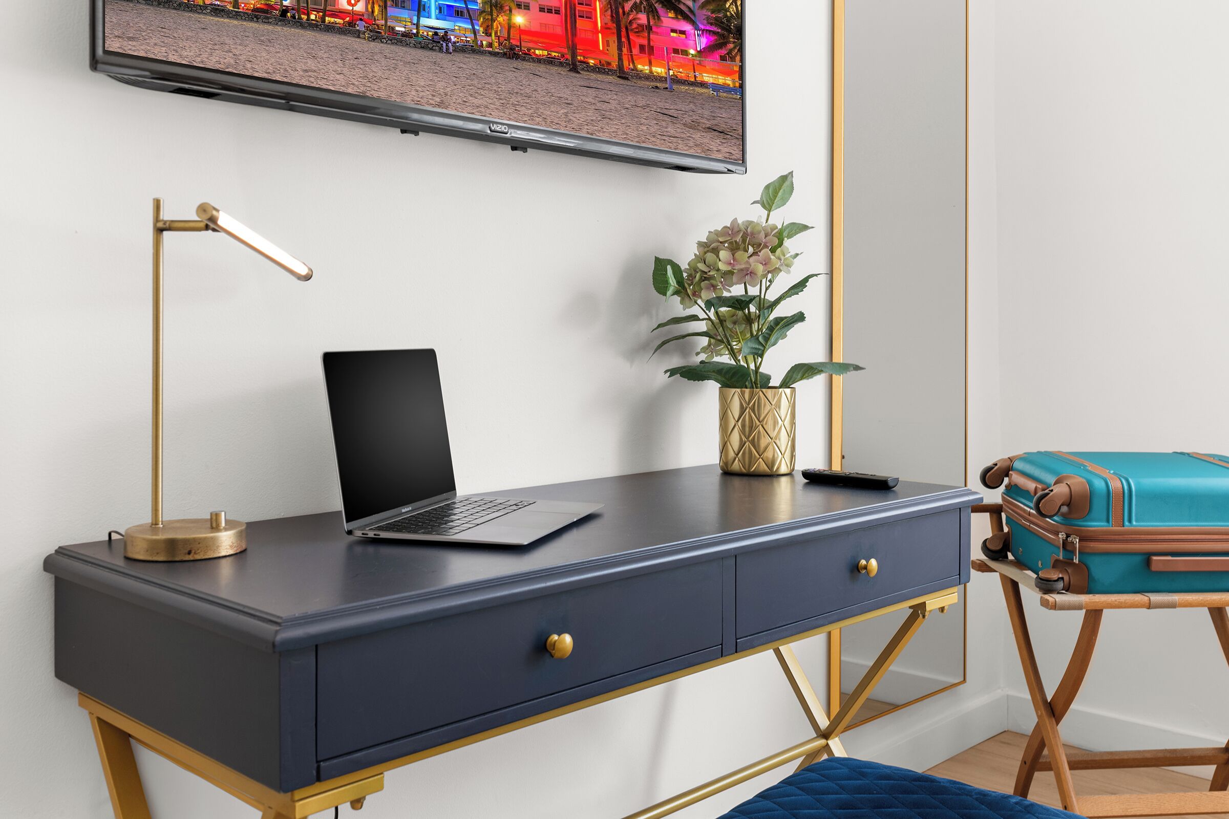 A modern room with a desk, laptop, and a television mounted on the wall.