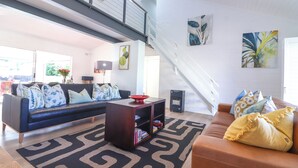 A modern living room with a black sectional sofa, a brown leather couch, and a patterned rug. - Tranquil 3-bedroom house in charming Onrusrivier for your getaway (Onrusrivier)