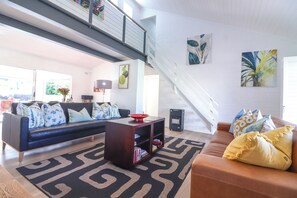 A modern living room with a black sectional sofa, a brown leather couch, and a patterned rug. - Tranquil 3-bedroom house in charming Onrusrivier for your getaway (Onrusrivier)