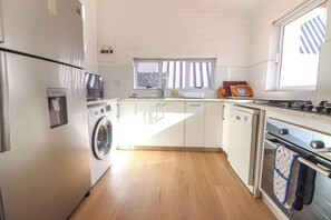 Eine kleine Küche mit Waschmaschine, Mikrowelle und Backofen.