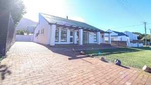 A residential building with a paved driveway and a well-maintained lawn. - Tranquil 3-bedroom house in charming Onrusrivier for your getaway (Onrusrivier)