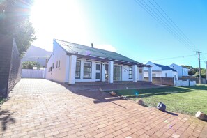 A residential building with a paved driveway and a well-maintained lawn. - Tranquil 3-bedroom house in charming Onrusrivier for your getaway (Onrusrivier)