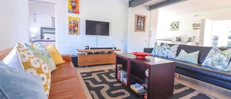 A modern living room with a sofa, coffee table, and a flat-screen TV mounted on the wall.