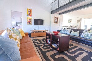 A modern living room with a sofa, coffee table, and a flat-screen TV mounted on the wall. - Tranquil 3-bedroom house in charming Onrusrivier for your getaway (Onrusrivier)