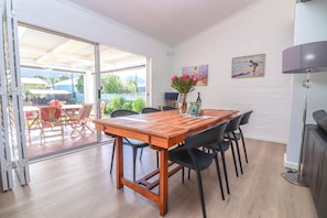 A dining area with a wooden table, black chairs, and a glass door leading to an outdoor patio. - Tranquil 3-bedroom house in charming Onrusrivier for your getaway (Onrusrivier)