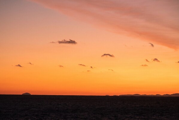 Un coucher de soleil sur un paysage plat, avec une étendue de terre visible au loin.