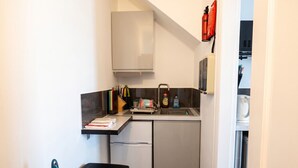 Een kleine keuken met een koelkast, spoelbak en een klein aanrecht.