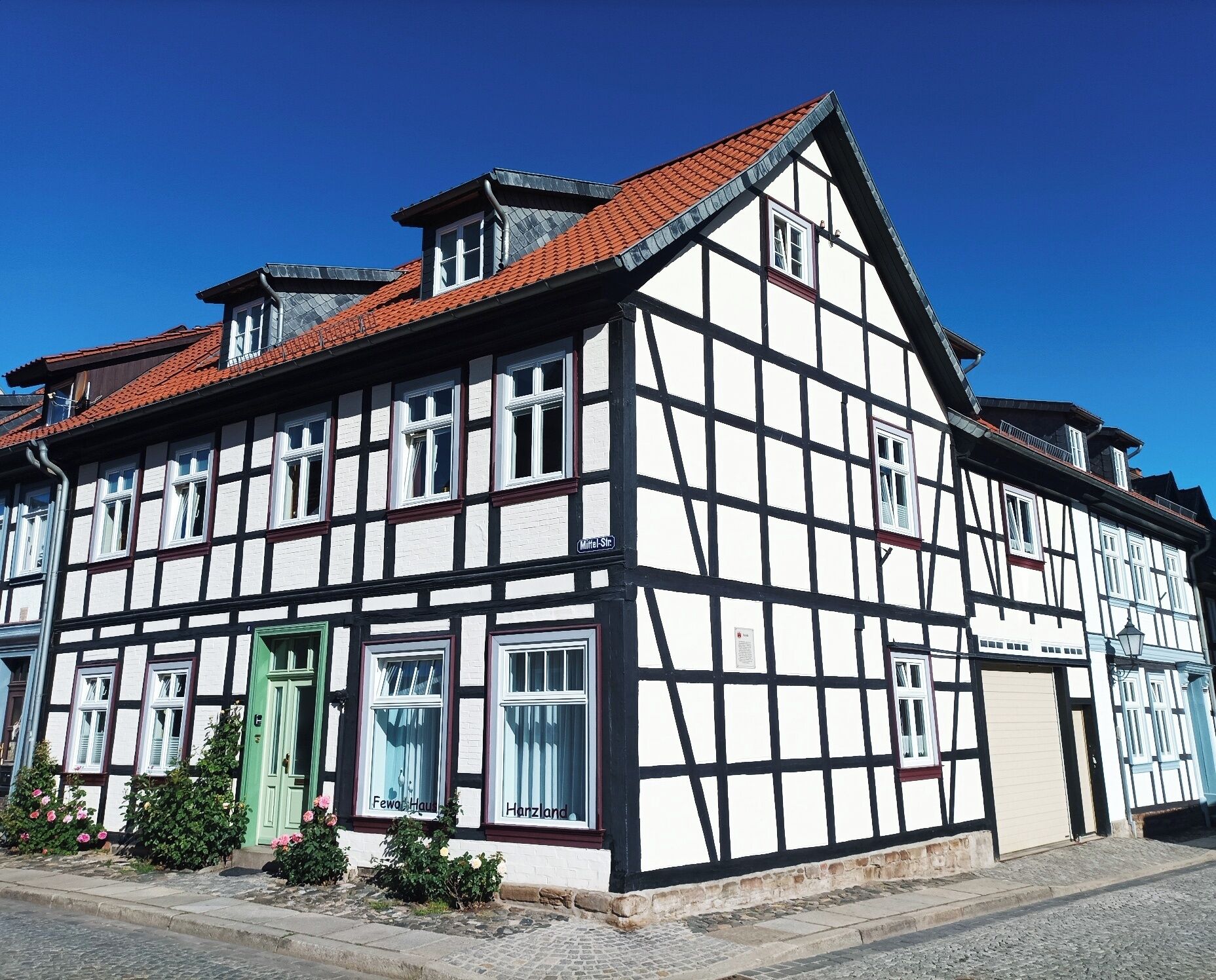 A traditional half-timbered building with a steeply pitched roof, multiple windows, and a green door.