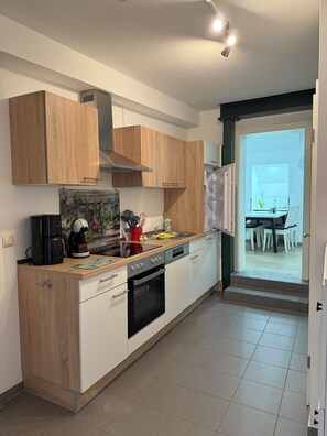 Eine moderne Küche mit Holzschränken, einem eingebauten Backofen und einem Essbereich mit Stühlen.
