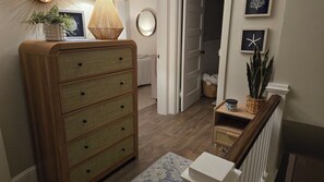A wooden dresser with drawers, a lamp, and a potted plant. - Cozy renovated century home retreat minutes away from Lake Erie. (Conneaut)