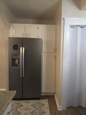 Eine Küche mit einem Edelstahl-Kühlschrank, weißen Schränken und einem gemusterten Teppich.